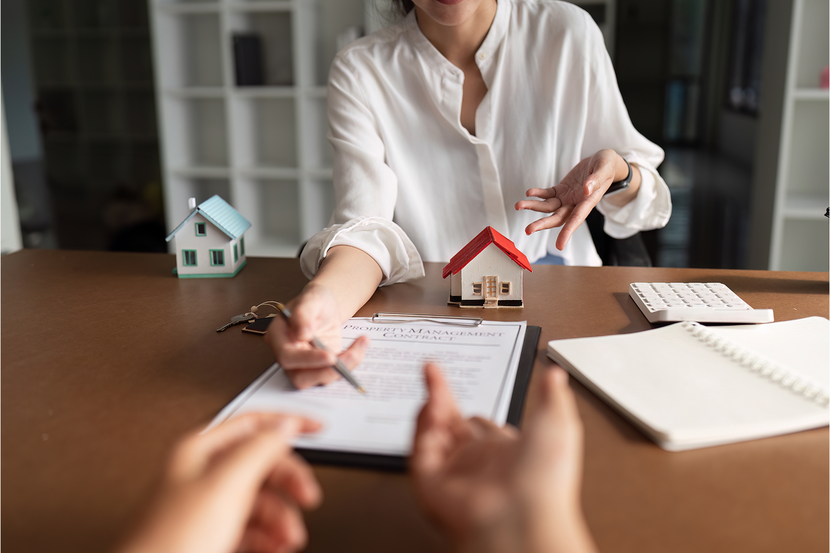 Person signing real estate contract with agent.
