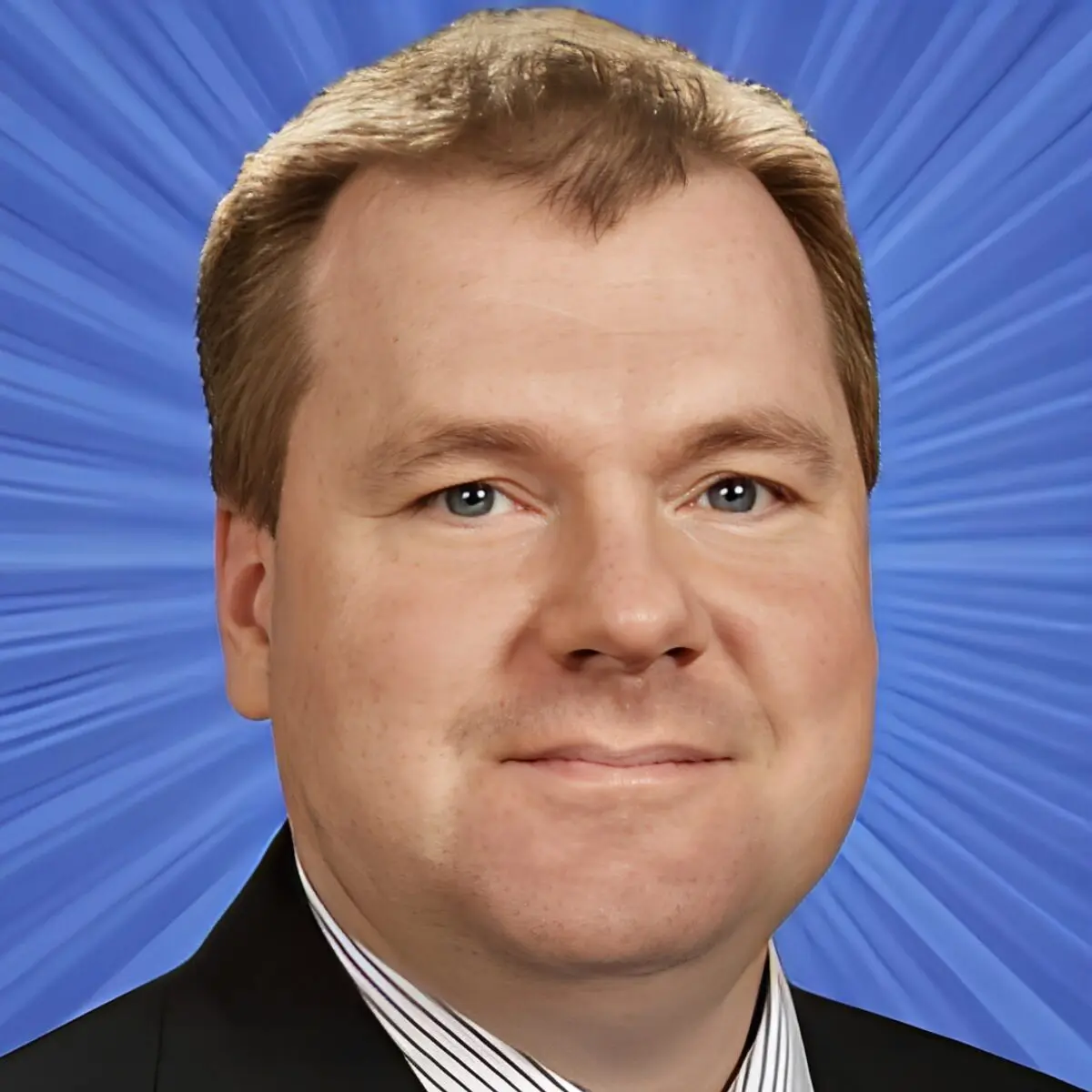 Man smiling in front of blue background.