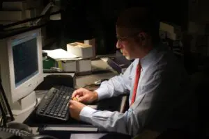Man working on computer in dim office.