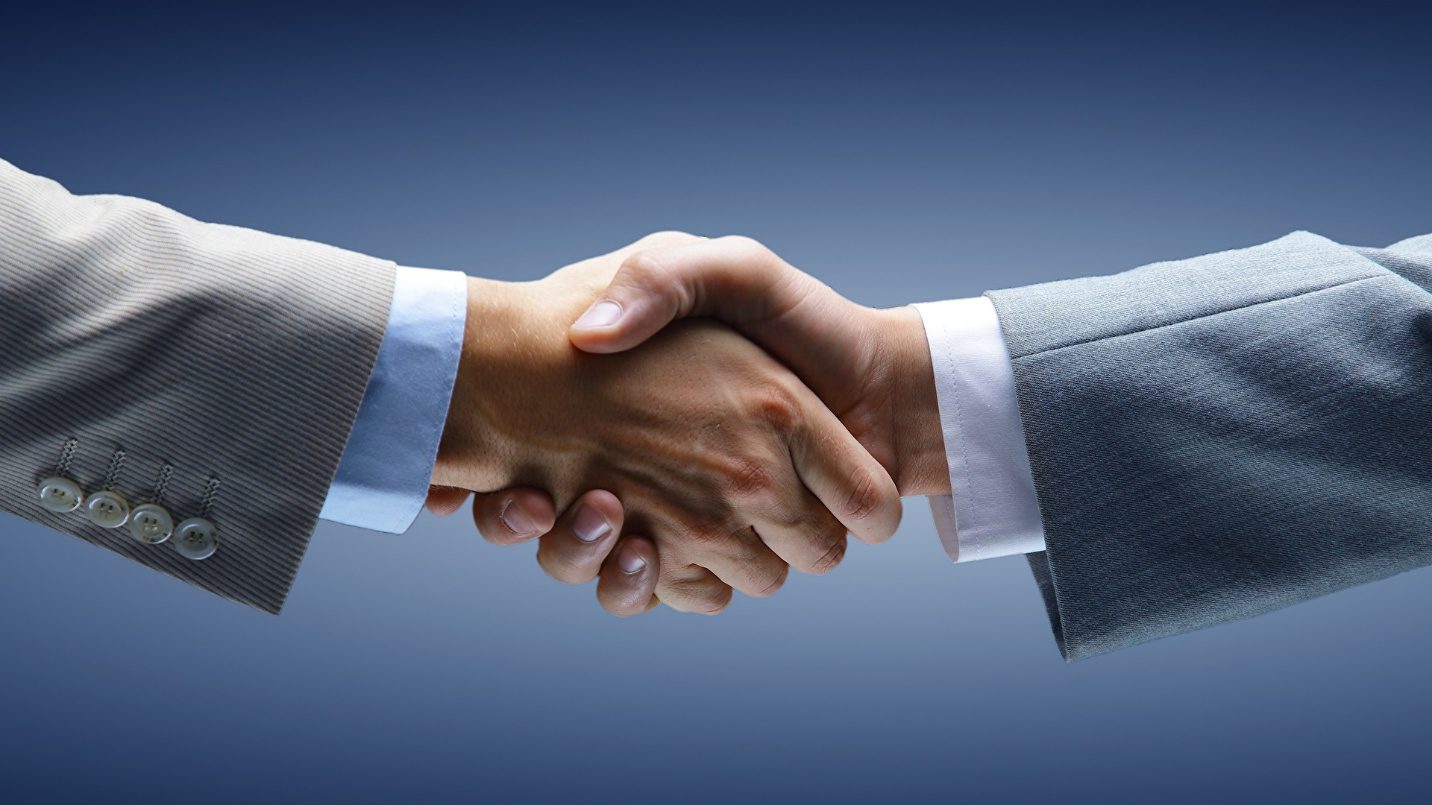 Business handshake between two people in suits.