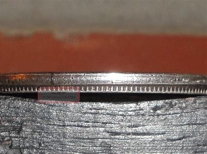 Edge of a coin on wood surface.