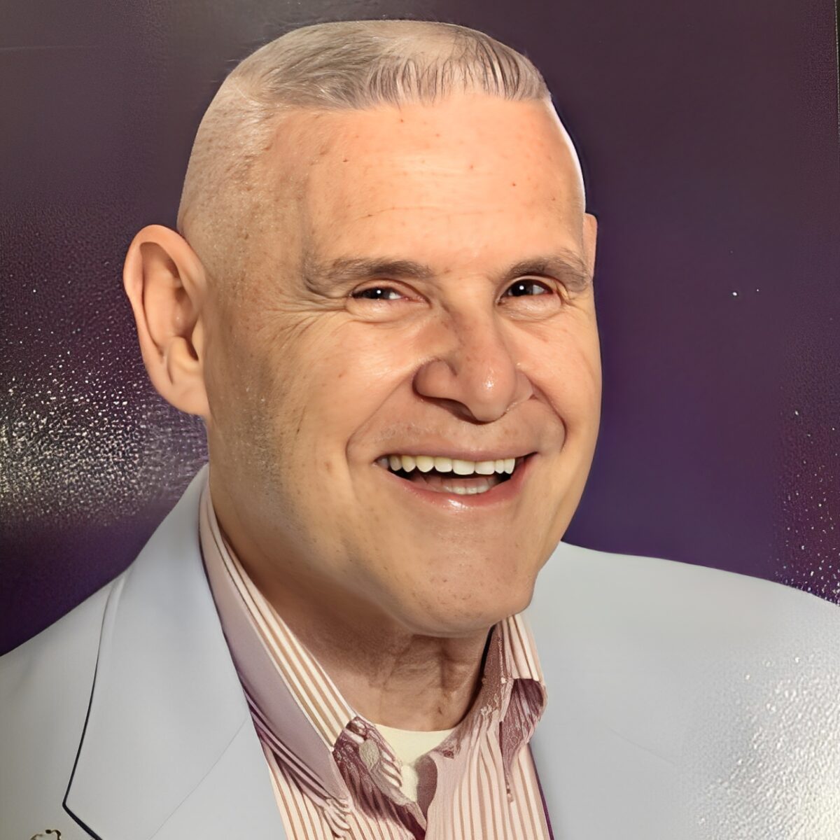 Smiling man in light blue suit jacket.
