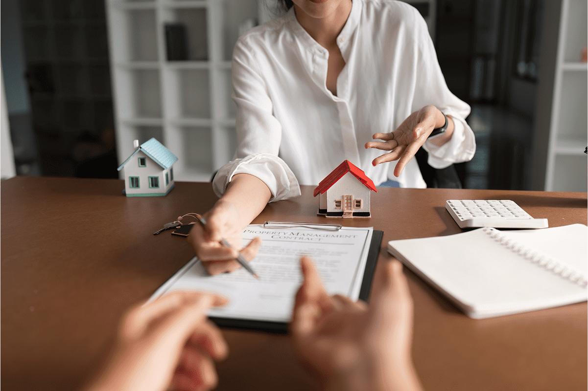 Person signing real estate contract with agent.