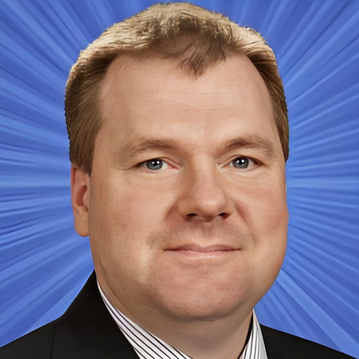 Man smiling in front of blue background.