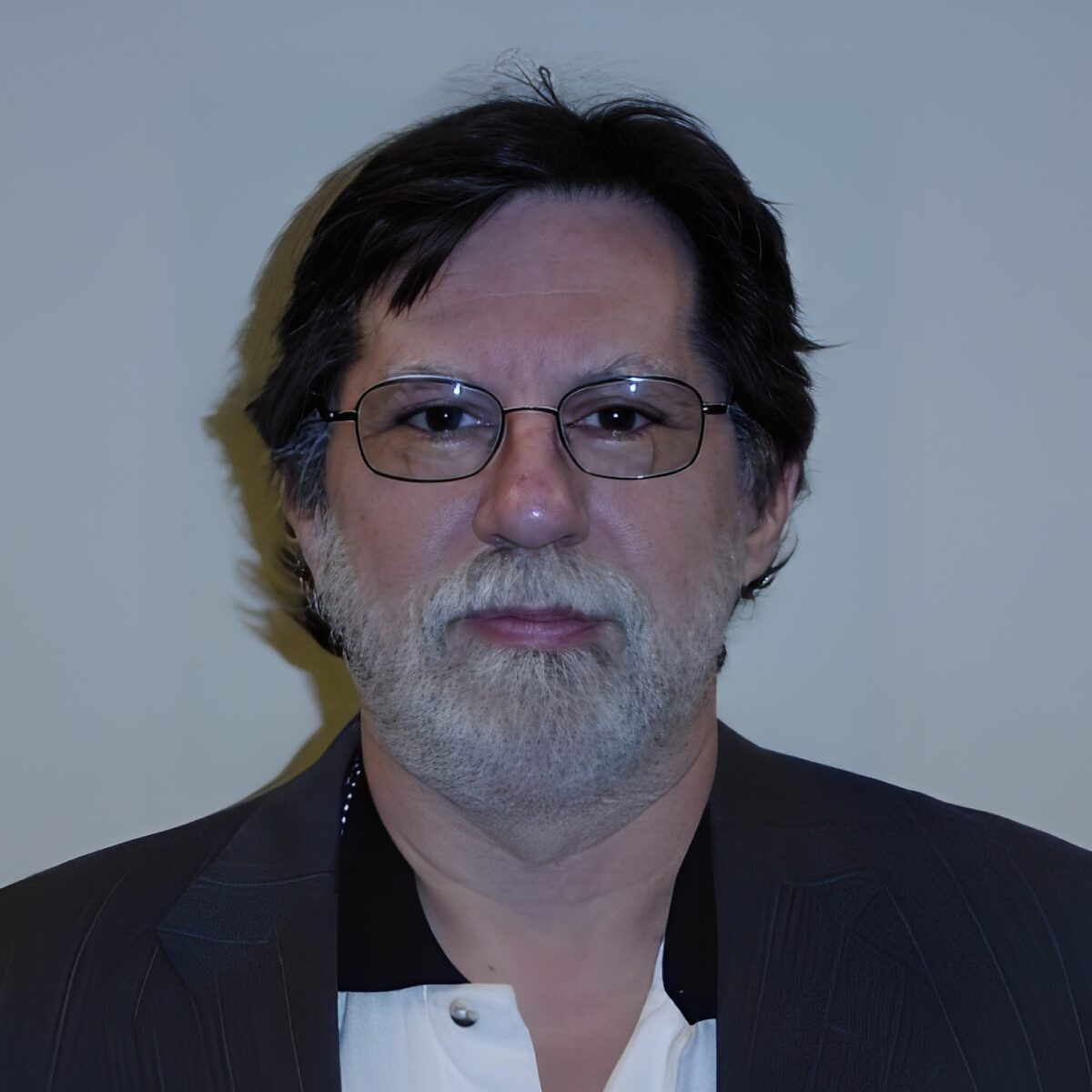 Man with glasses and beard in suit.