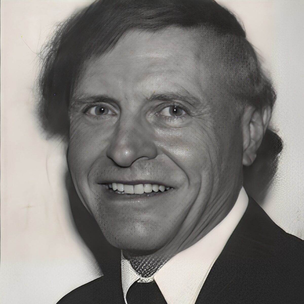 Smiling man in black and white portrait.