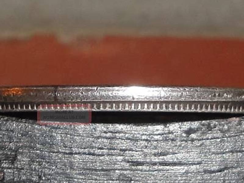 Close-up of a coin's edge showing detailed ridges.