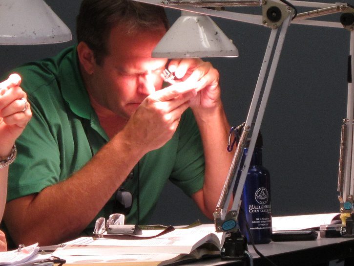 Man examining an object under bright lamp.