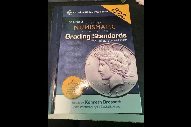Coin grading book with silver dollar cover.
