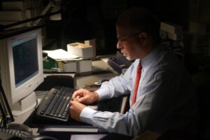 Man working on computer in dim office.