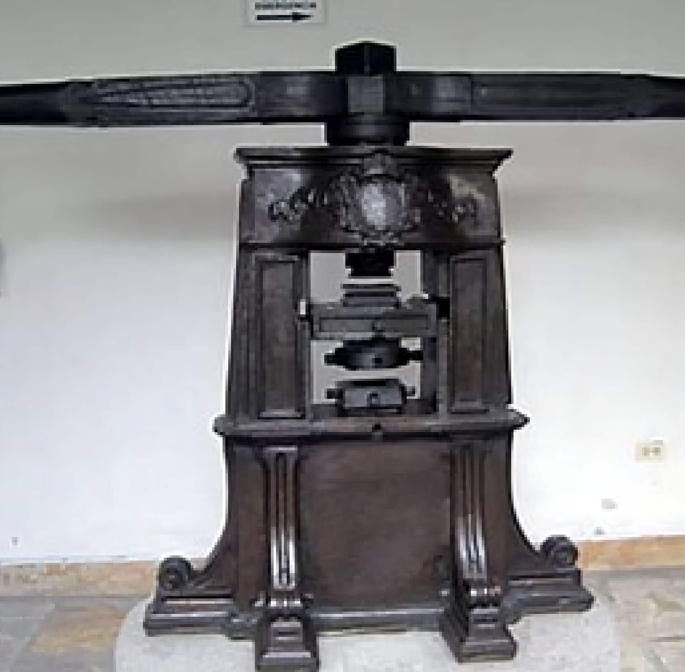 An antique black metal printing press on display indoors.