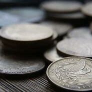 Close-up of stacked silver coins on a wooden surface.